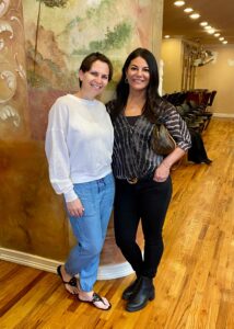 Two women who went through the Diva for a Day on Staten Island experience, standing next to each other in a salon. 