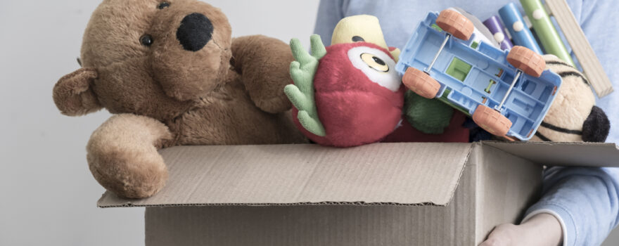 A person holding a donation box of toys, which is one idea for what to do with your kids’ old toys