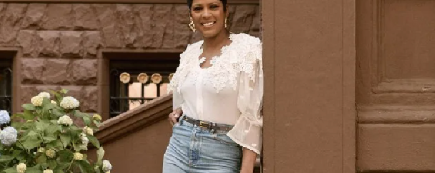 Tamron Hall leans on a post in front of her Harlem brownstone, son Moses in foreground.