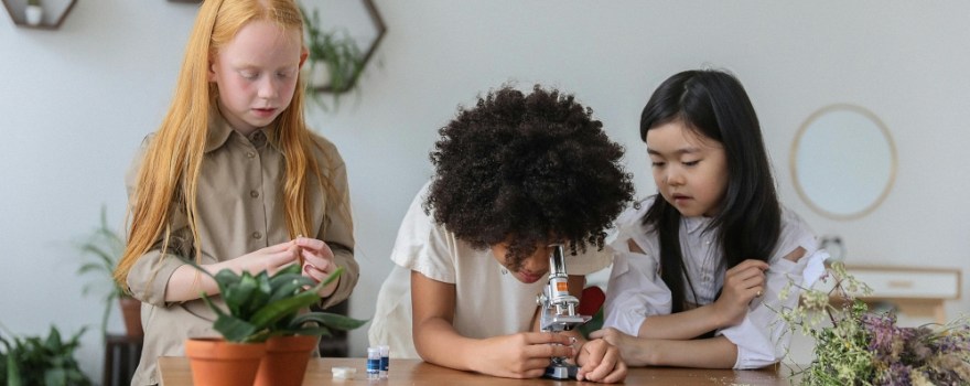 Kids look through a microscope similar to the STEAM NYPL kit.